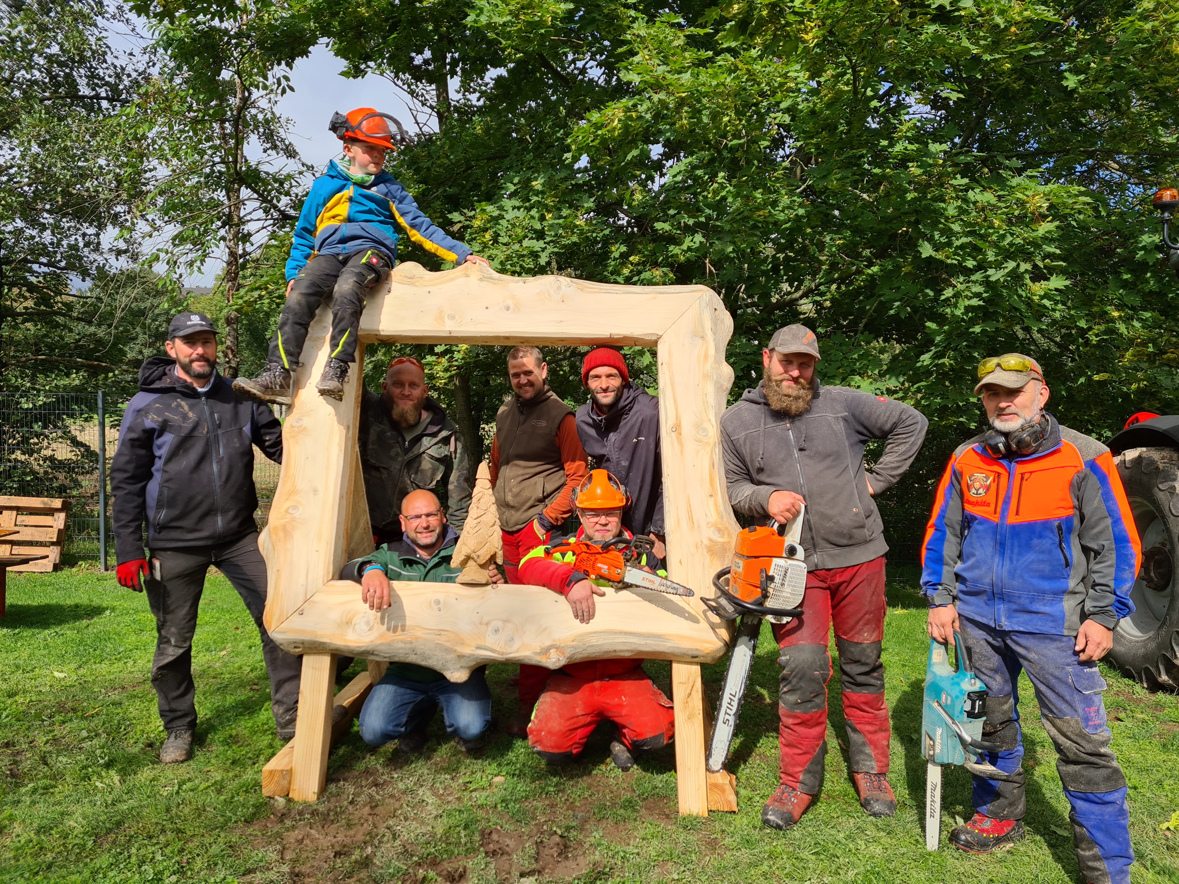 Bild aller Künstler vor einem selbst geschnitzten Holzrahmen